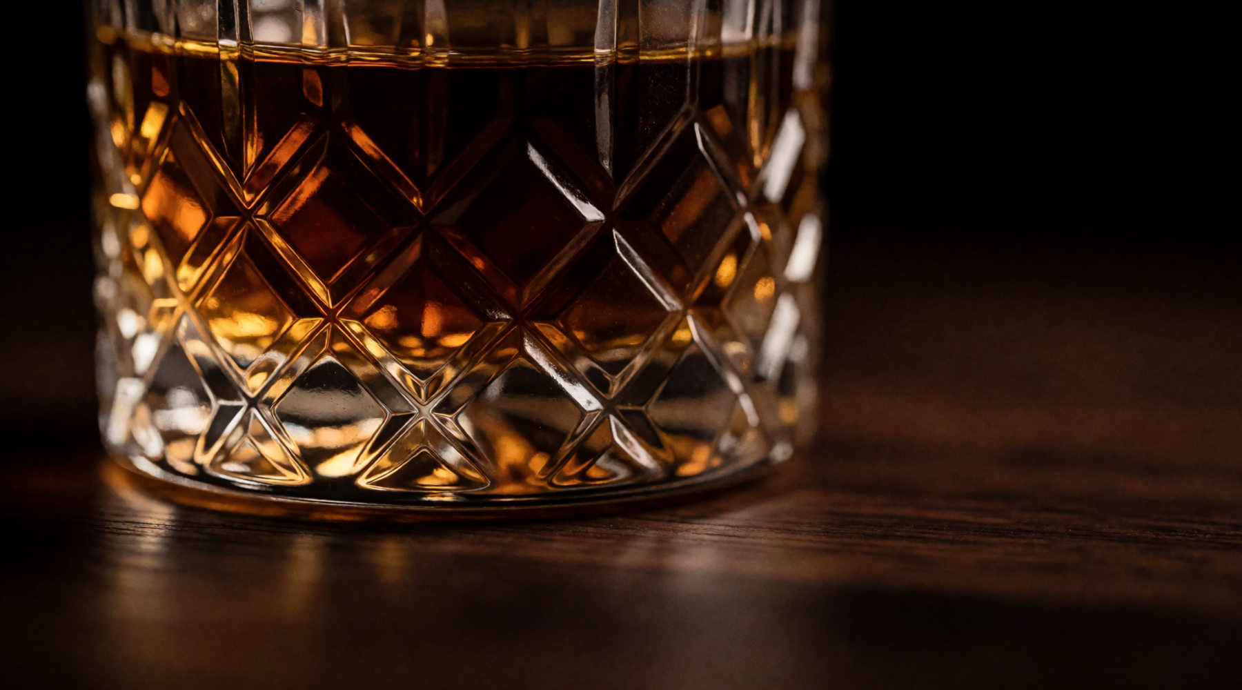 Whisky in a cut-crystal tumbler, lit from one side.